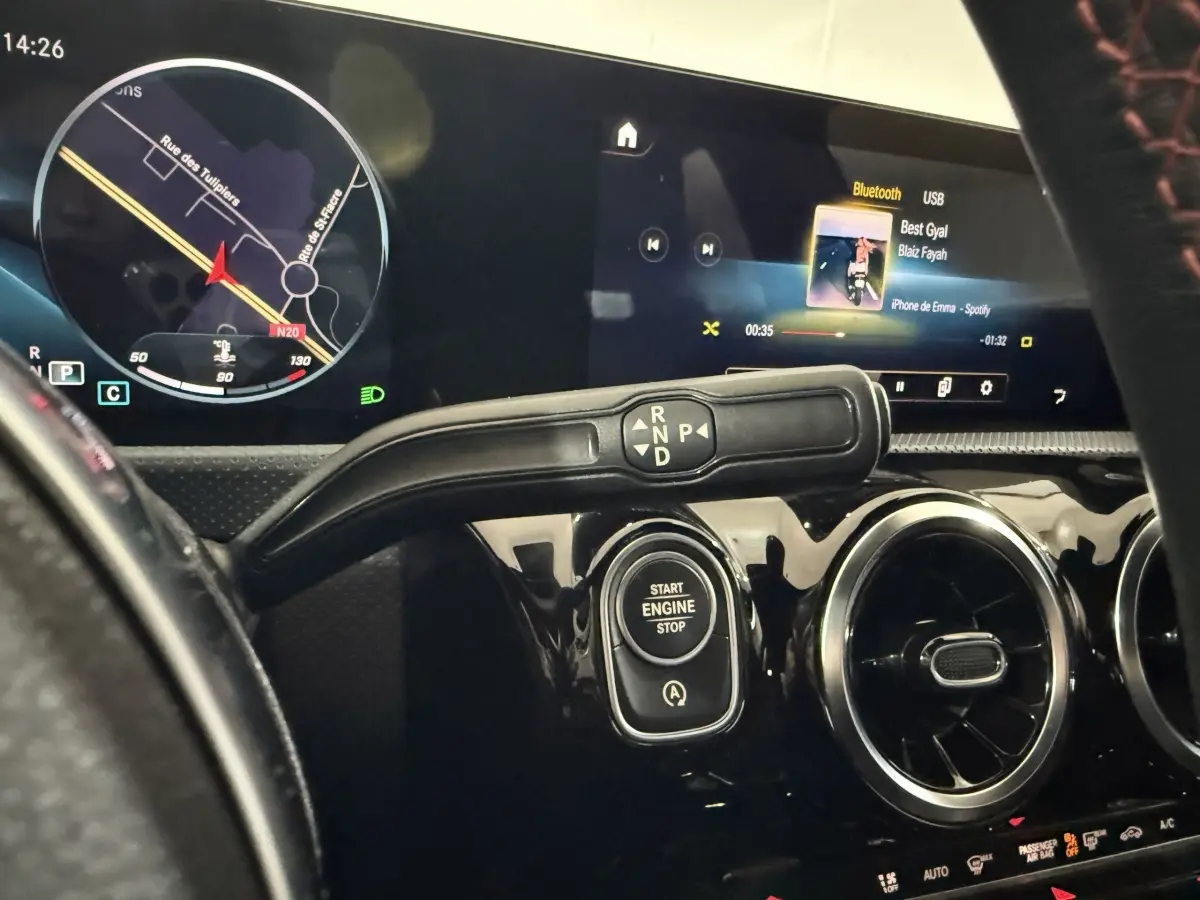 Vue rapprochée du tableau de bord noir brillant d’une Mercedes Classe A 200 AMG Line 2021, avec écran tactile et bouton start/stop.