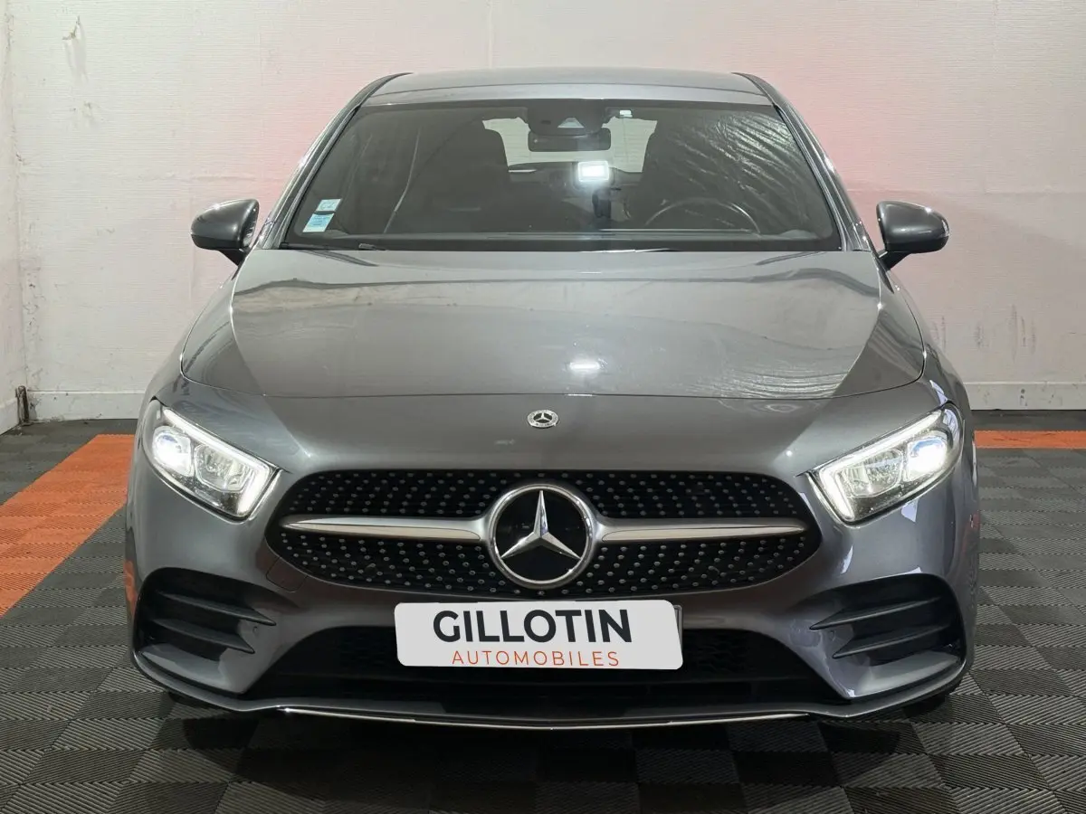 Vue frontale d'une Mercedes Classe A 200 AMG Line gris foncé avec phares LED allumés dans un showroom.