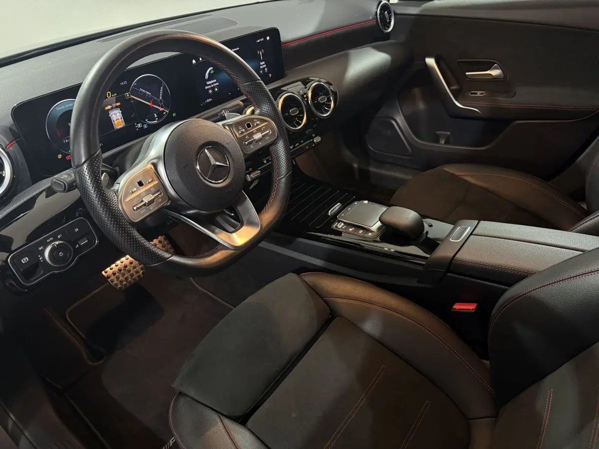 Intérieur de la Mercedes Classe A 200 AMG Line 2021, vue côté conducteur, volant cuir, écran tactile et sièges noirs.