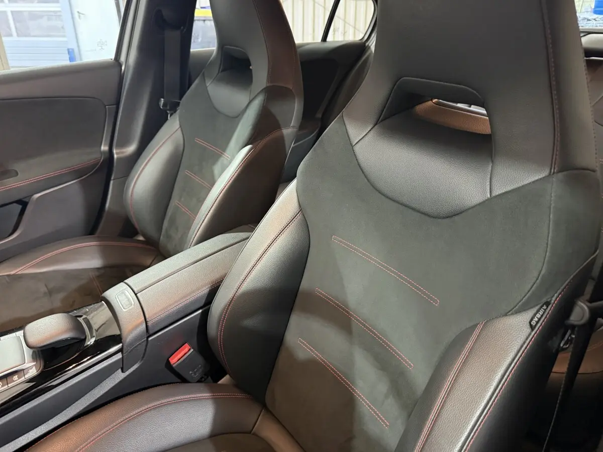 Vue rapprochée des sièges avant sport noirs avec surpiqûres rouges dans l’habitacle d’une Mercedes Classe A AMG Line 2021.
