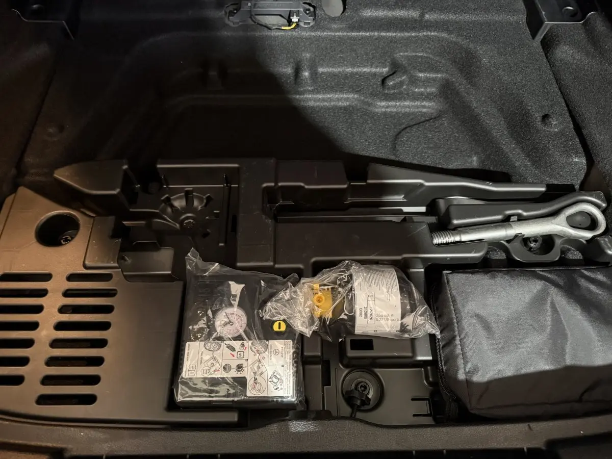 Vue rapprochée du coffre de la Mercedes Classe A 200 AMG Line 2021, montrant le kit de réparation pneu et outils intégrés.