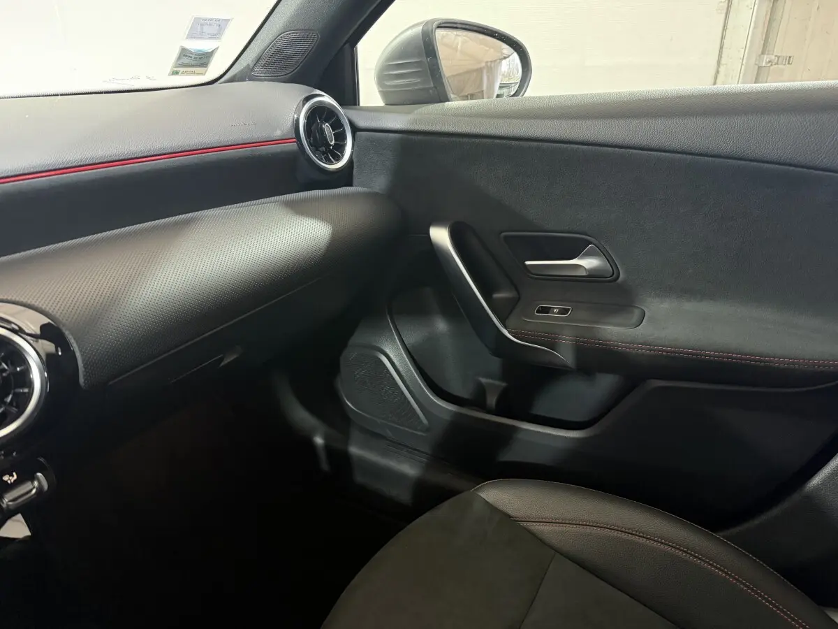 Vue intérieure côté passager de la Mercedes Classe A 200 AMG Line 2021, tableau de bord noir avec surpiqûres rouges.