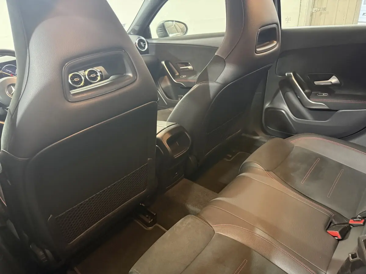 Vue intérieure arrière côté droit de la Mercedes Classe A 200 AMG Line 2021 avec sièges cuir noir et surpiqûres rouges.