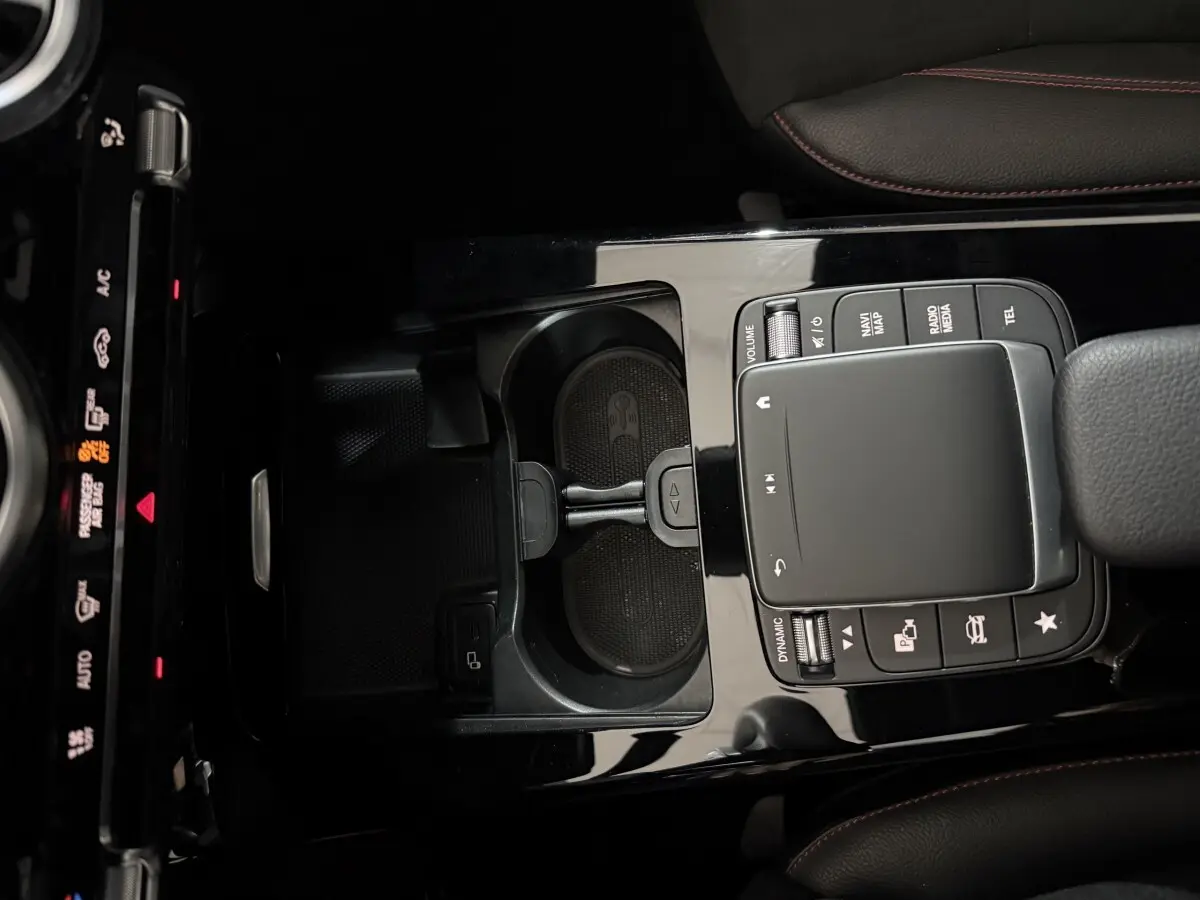 Gros plan sur la console centrale noire brillante de la Mercedes Classe A A 200 AMG Line avec pavé tactile et commandes multimédia.