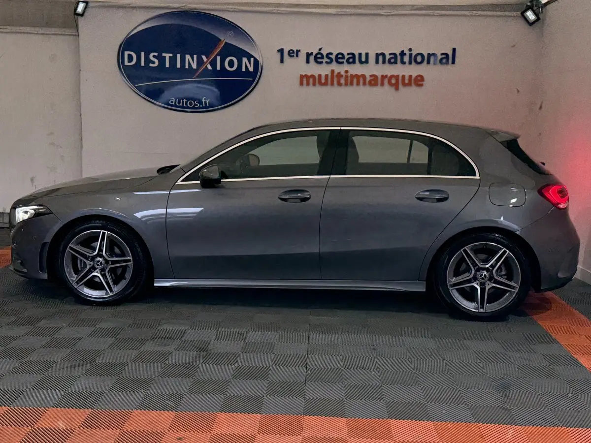 Vue de profil côté gauche d'une Mercedes Classe A 200 AMG Line gris foncé avec jantes alliage et feux arrière allumés.