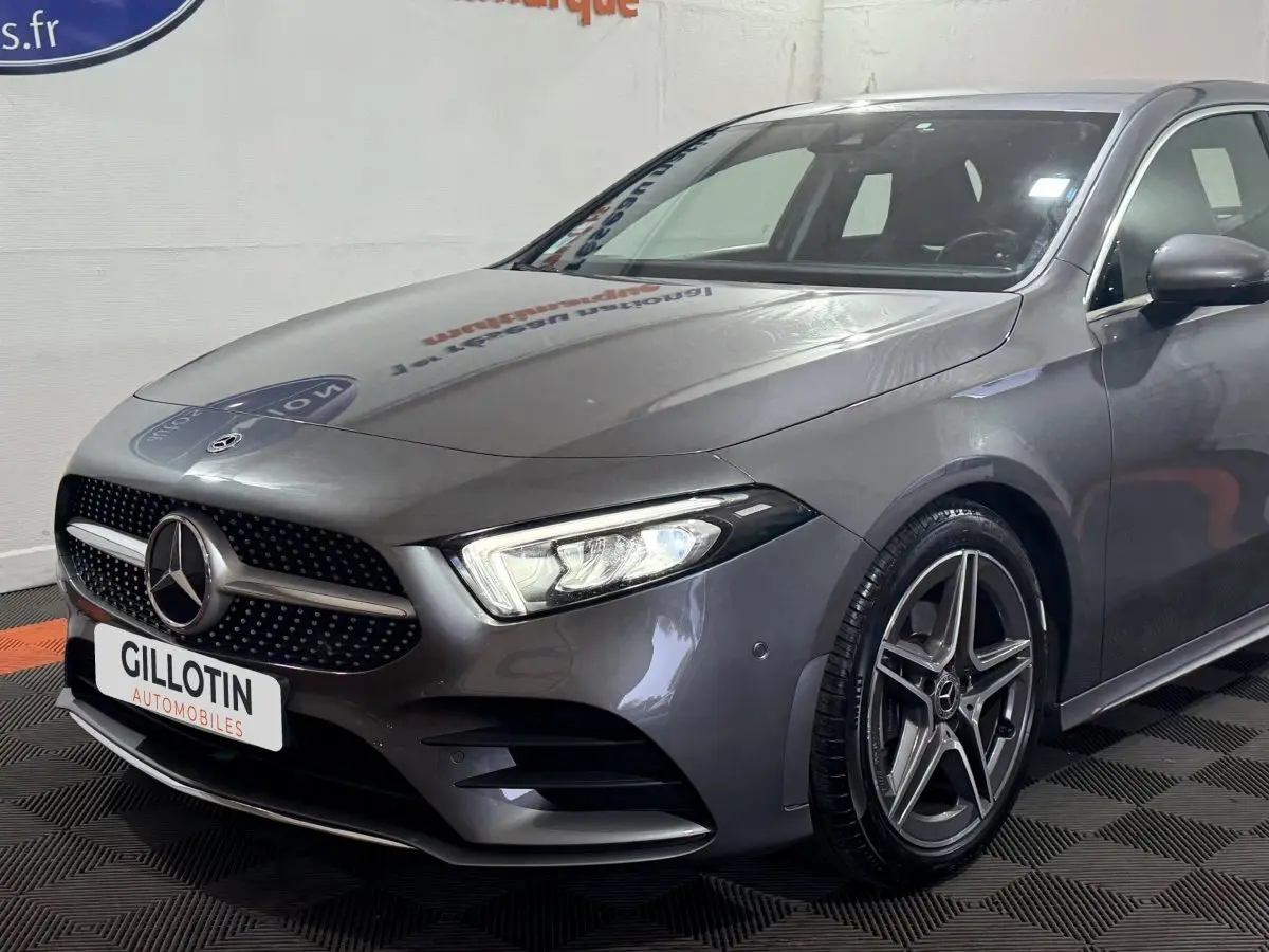 Vue 3/4 avant droit d'une Mercedes Classe A 200 AMG Line gris foncé avec calandre étoilée et jantes alliage cinq branches.