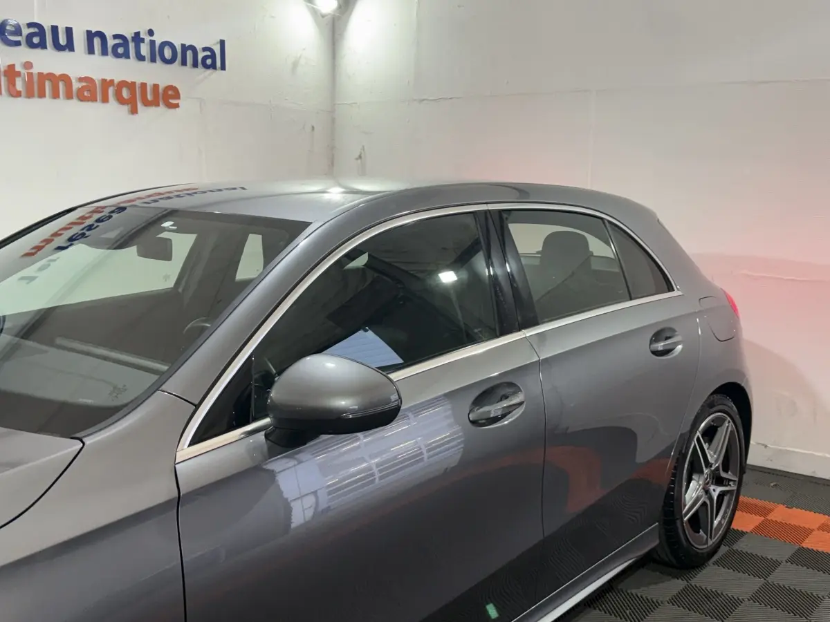 Vue côté gauche d'une Mercedes Classe A 200 AMG Line gris foncé, mettant en valeur les jantes alliage et les rétroviseurs électriques.