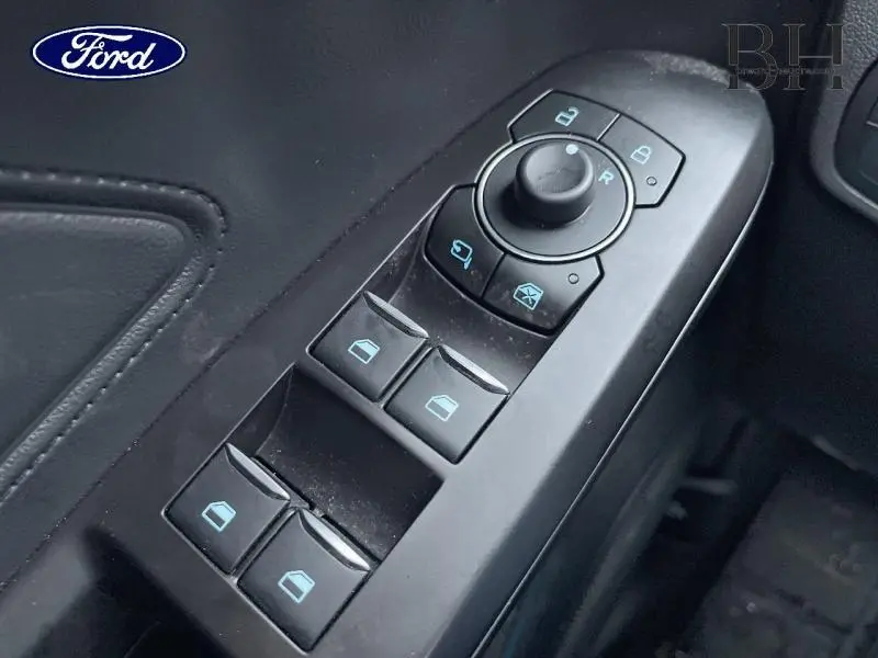 Gros plan sur les commandes de lève-vitres et rétroviseurs électriques côté conducteur du Ford Focus SW noir Agate 2024.