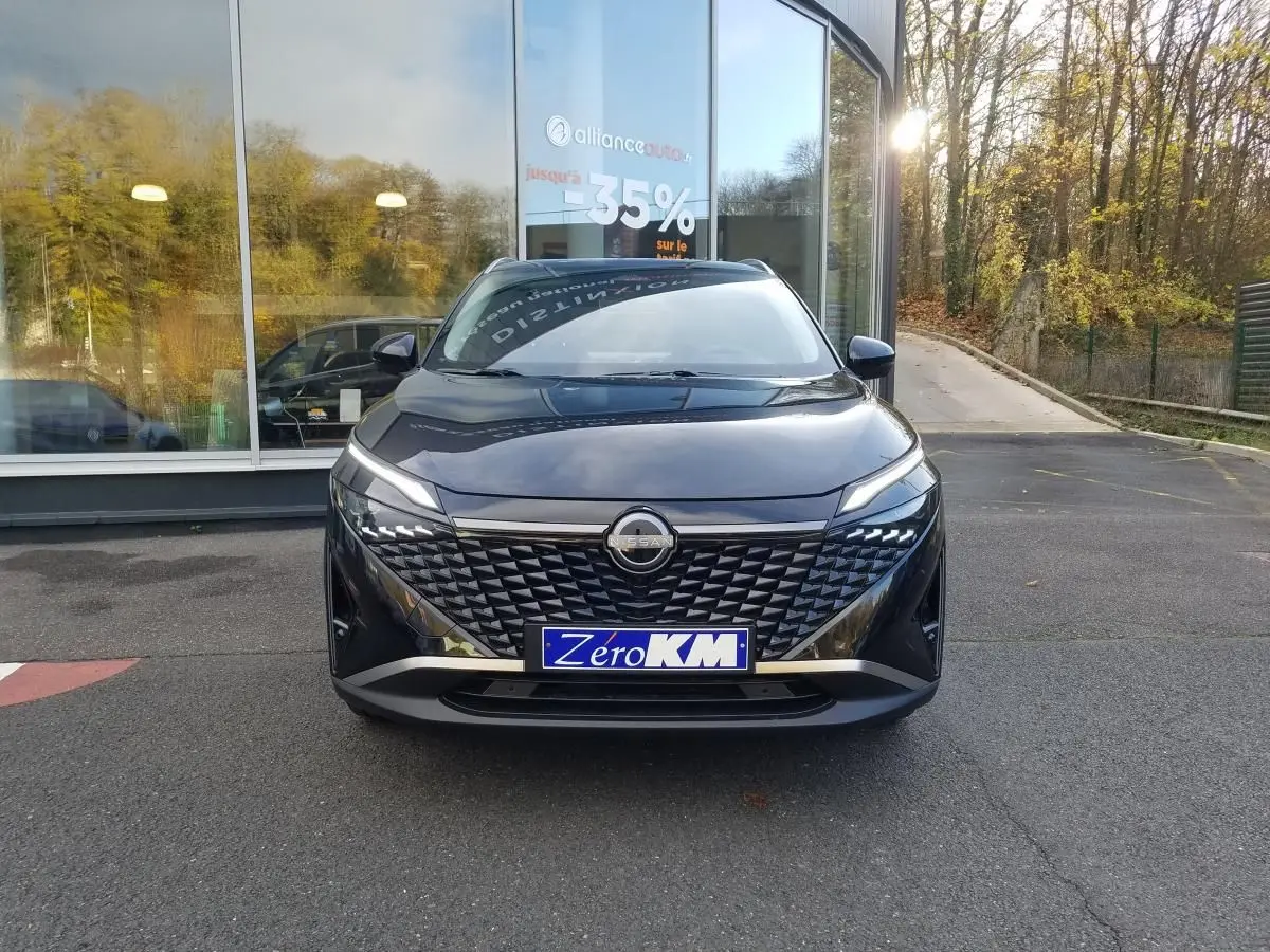 Vue avant d'un Nissan Qashqai noir 2025 avec calandre texturée et phares LED fins, stationné devant une vitrine.