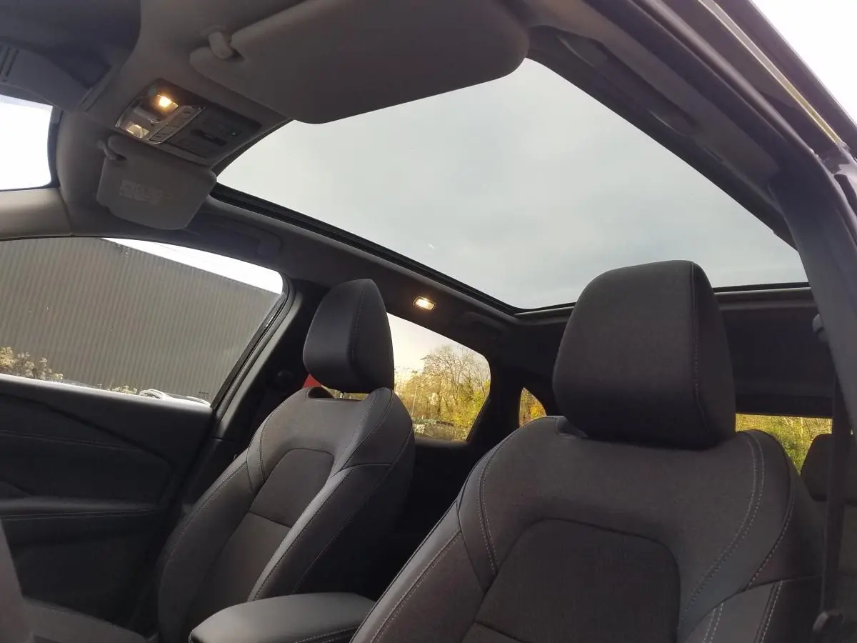 Vue intérieure avant du Nissan Qashqai noir 2025, mettant en valeur les sièges et le toit panoramique en verre.