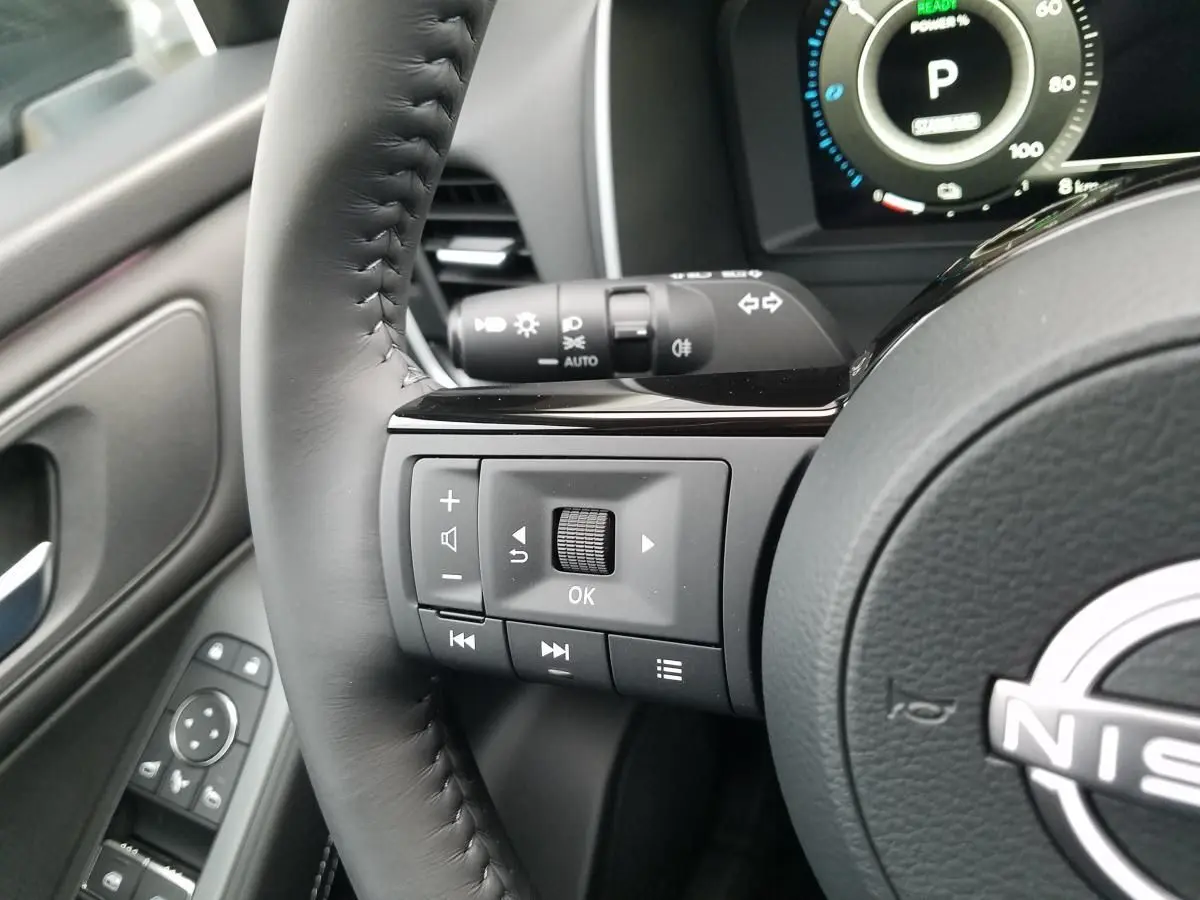 Gros plan sur le volant noir du Nissan Qashqai 2025 montrant les commandes multifonctions à gauche et le tableau de bord numérique.