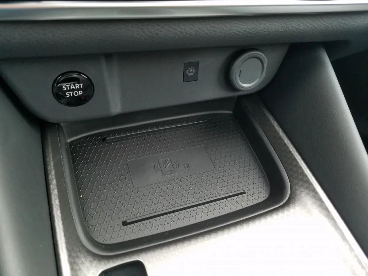 Gros plan intérieur sur le chargeur à induction noir et le bouton Start/Stop du Nissan Qashqai 1.5 E-POWER 2025.