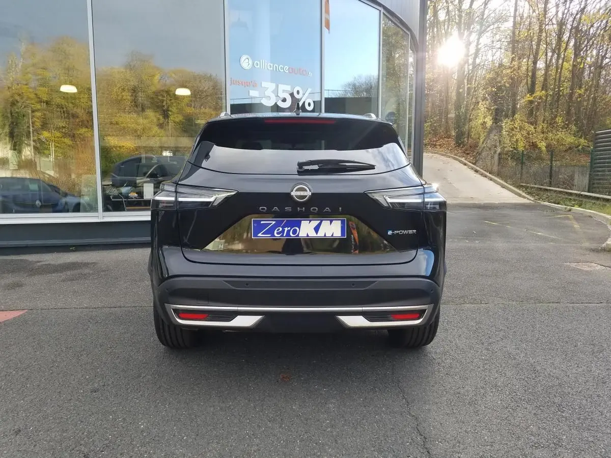 Vue arrière d'un Nissan Qashqai noir 2025 avec toit panoramique et logo e-Power visible au soleil.
