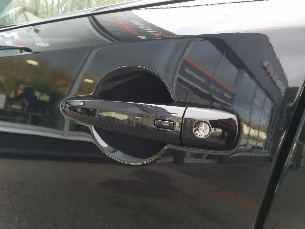 Poignée de porte avant droite noire du Nissan Qashqai 2025 avec serrure et bouton de déverrouillage.