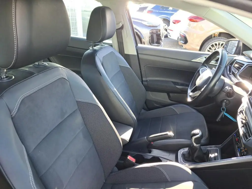 Vue intérieure côté droit de la Volkswagen Polo 1.0 TSI 95 Style 2022, sièges noirs avec surpiqûres blanches et levier de vitesses manuel.