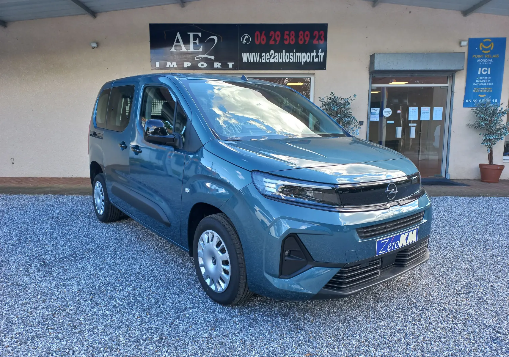 Opel Combo Life bleu kiama en 3/4 avant droit, avec calandre noire et jantes acier, stationné devant un bâtiment.