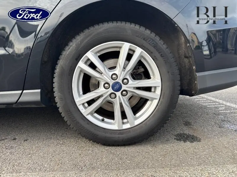 Gros plan sur la roue avant droite en jante alu d'une Ford S-MAX 2018 noire Mica Shadow, montrant le logo Ford central.