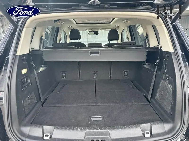 Vue arrière du coffre ouvert du Ford S-MAX noir Mica Shadow, montrant les sièges arrière rabattus et le toit panoramique.