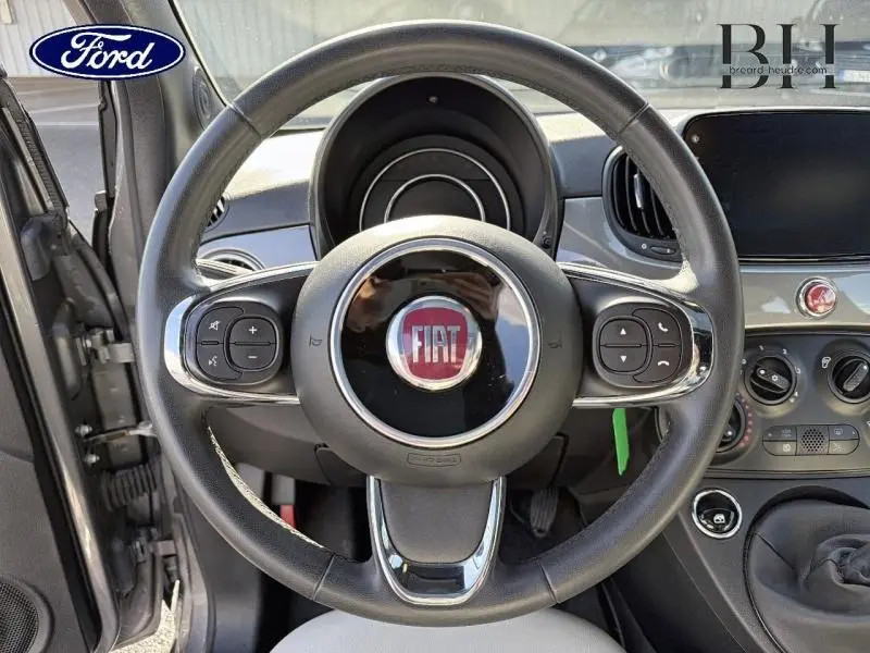 Vue rapprochée du volant cuir multifonction noir avec logo FIAT rouge au centre, tableau de bord et commandes visibles.