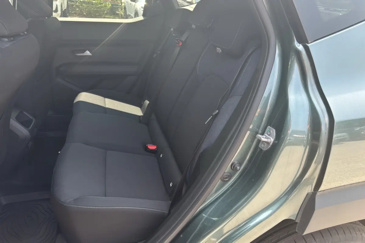 Vue côté droit sur la banquette arrière noire du Dacia Duster HEV 140 Journey Plus vert cèdre 2025 avec porte ouverte.