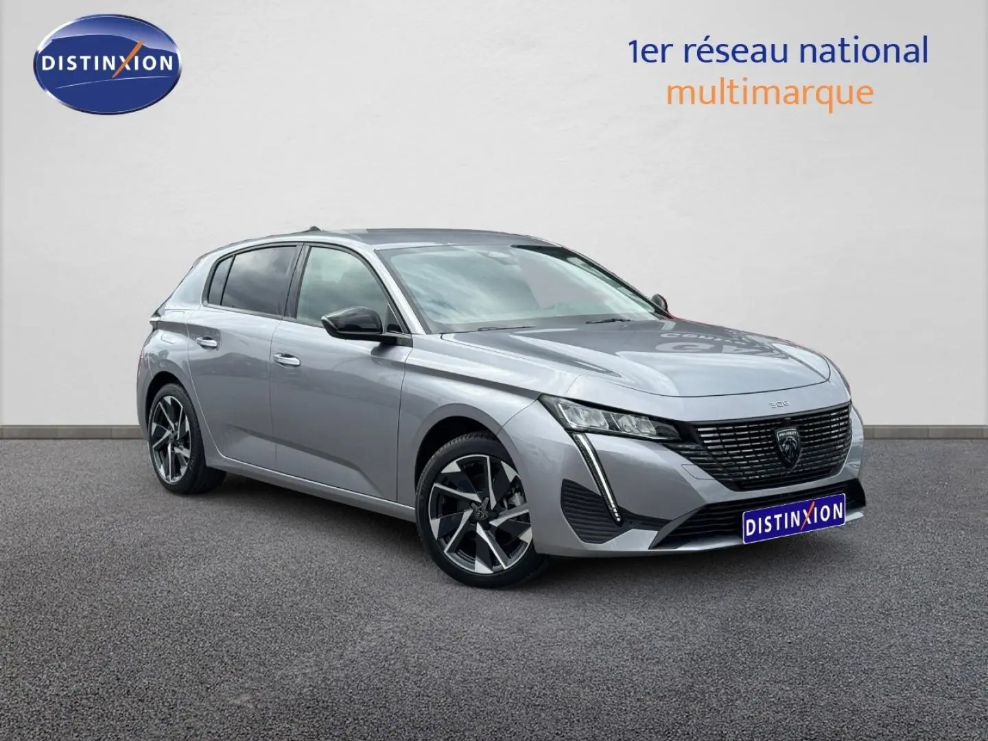Peugeot 308 gris Artense vue 3/4 avant droit, avec calandre noire et jantes alliage distinctives.