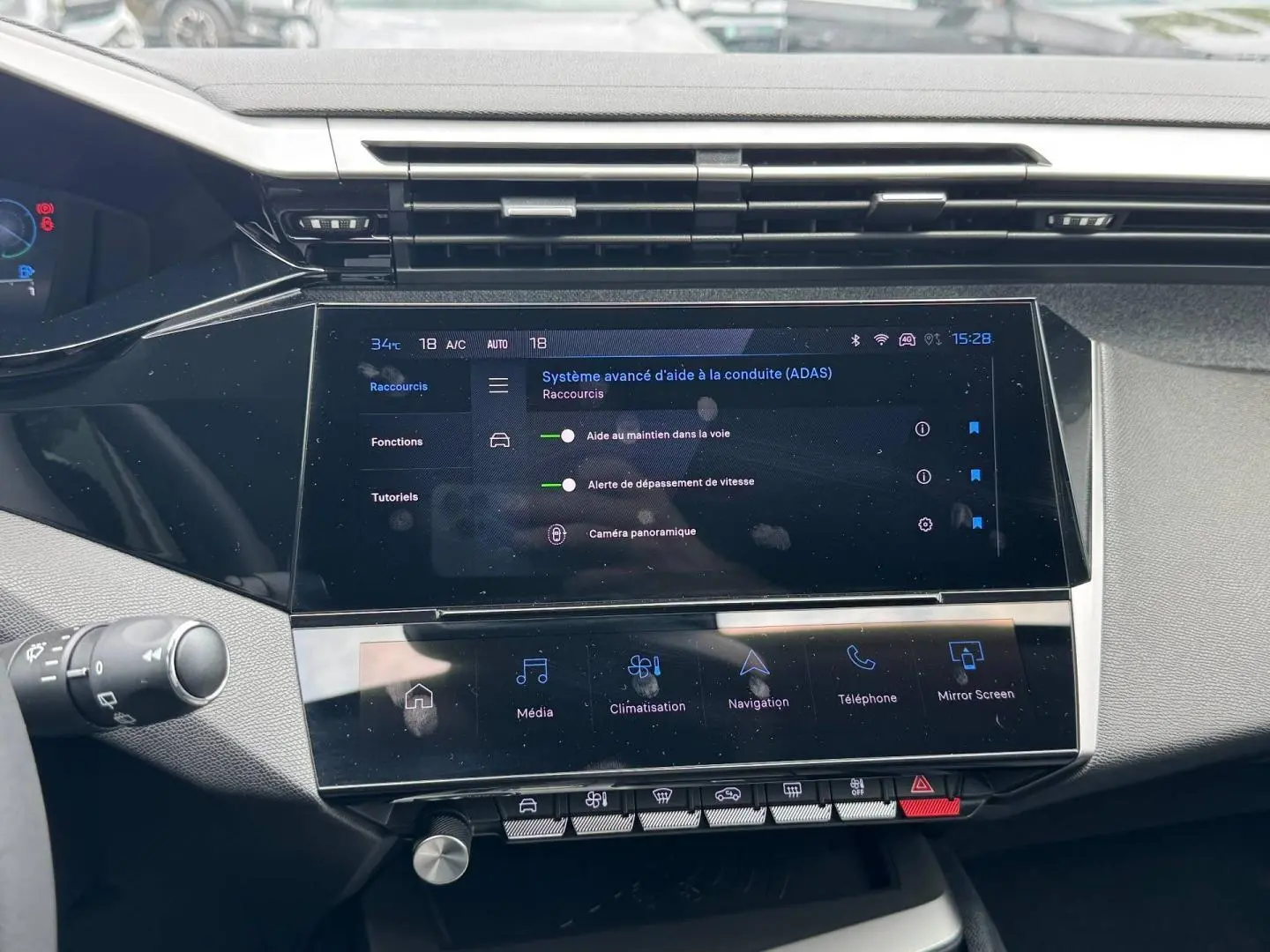 Vue rapprochée de la console centrale tactile de la Peugeot 308 Hybrid 2025 avec affichage des aides à la conduite.