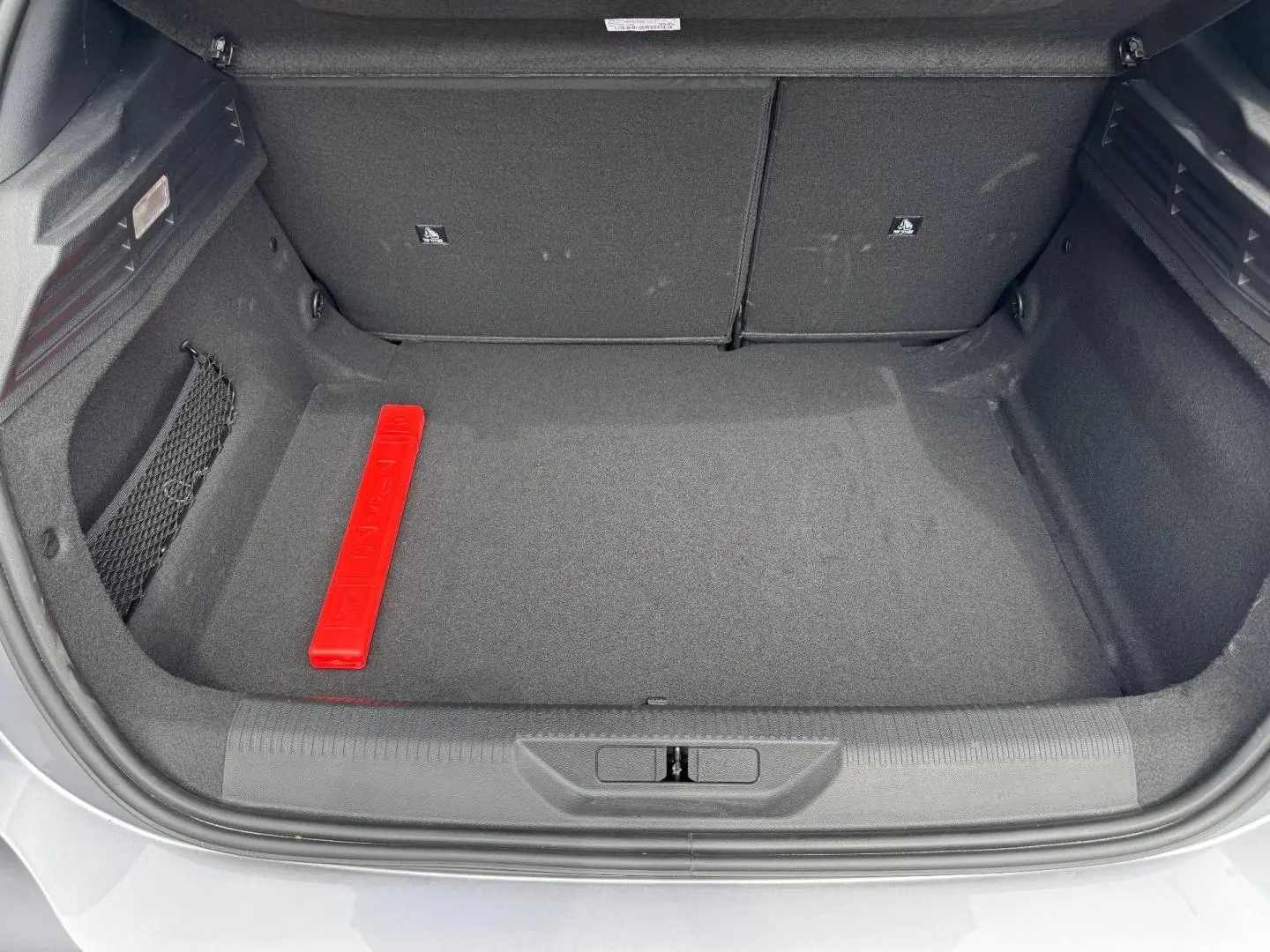 Coffre ouvert de Peugeot 308 gris Artense, vue de dessus montrant un espace de rangement propre avec triangle de sécurité rouge.