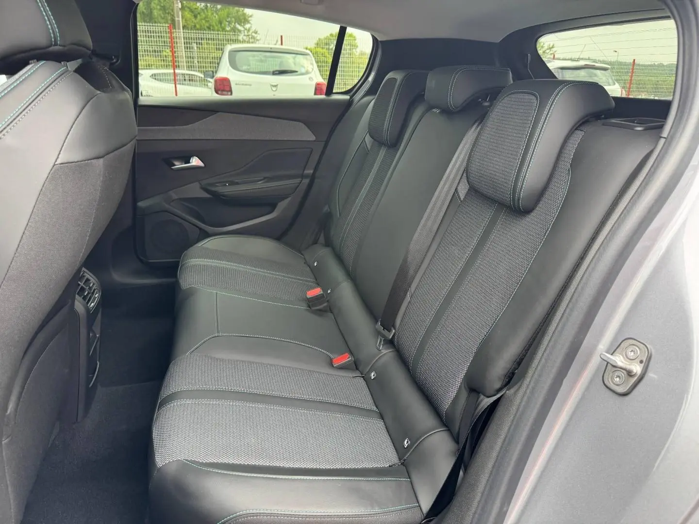 Vue intérieure côté droit des sièges arrière en tissu et cuir noir avec surpiqûres bleues d'une Peugeot 308 gris Artense 2025.