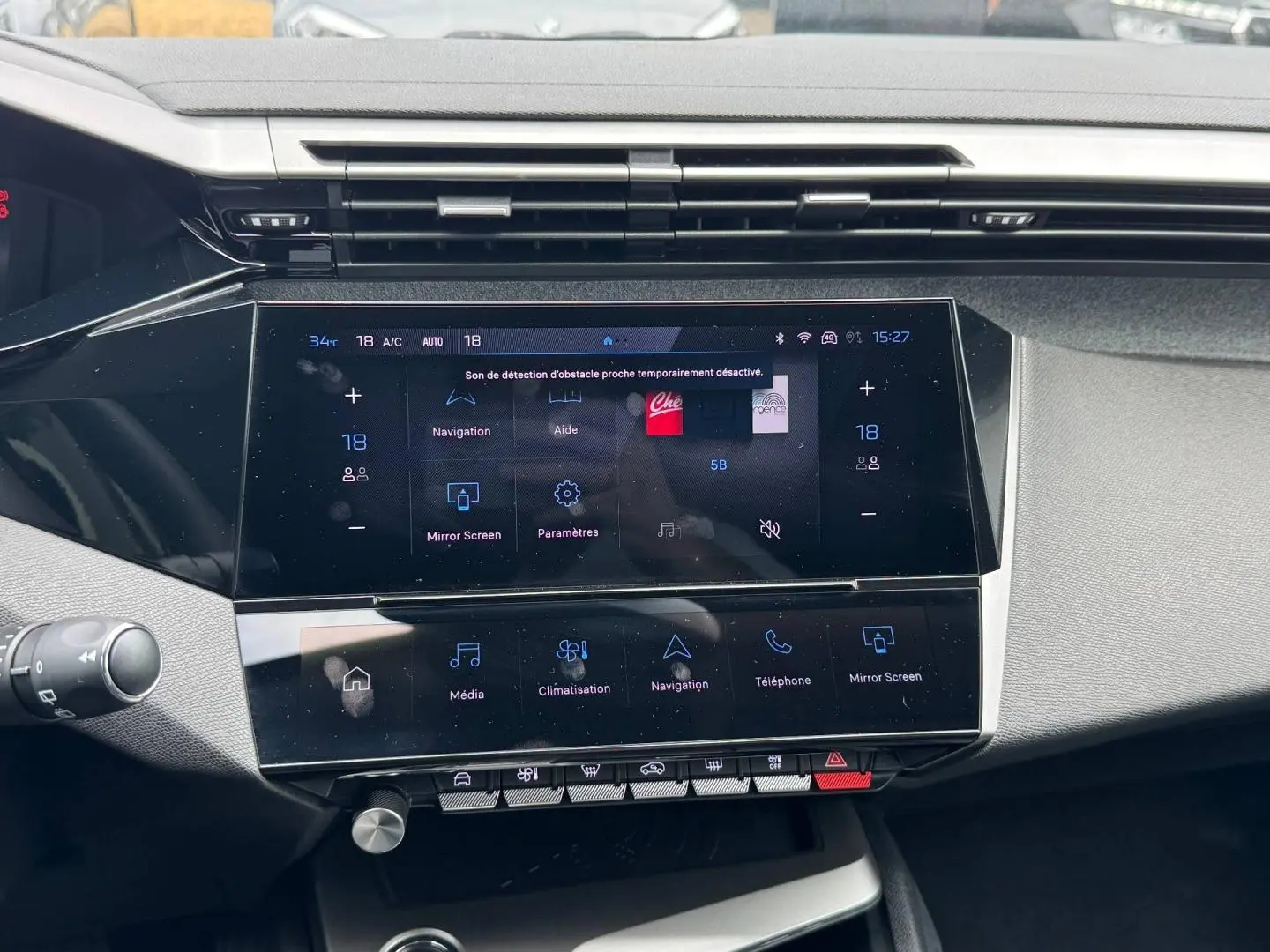 Vue rapprochée de l’écran tactile central multifonction de la Peugeot 308 gris Artense, avec commandes digitales et boutons physiques.