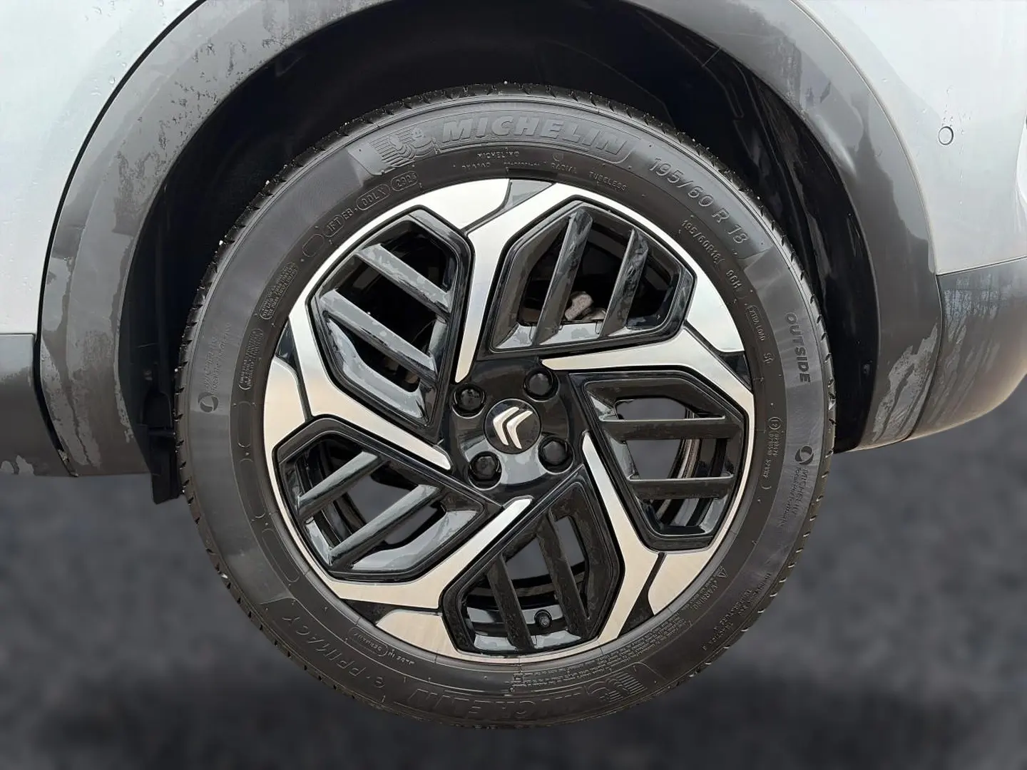 Gros plan sur la jante alu bicolore noire et argentée d'une Citroën C4 gris 2024, avec logo Citroën central.