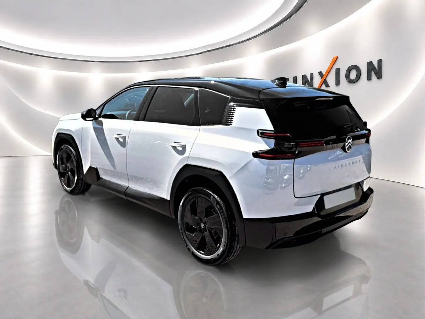 Vue 3/4 arrière droite du Citroën C5 Aircross hybride blanc et noir avec jantes alliage 19 pouces dans un showroom lumineux.