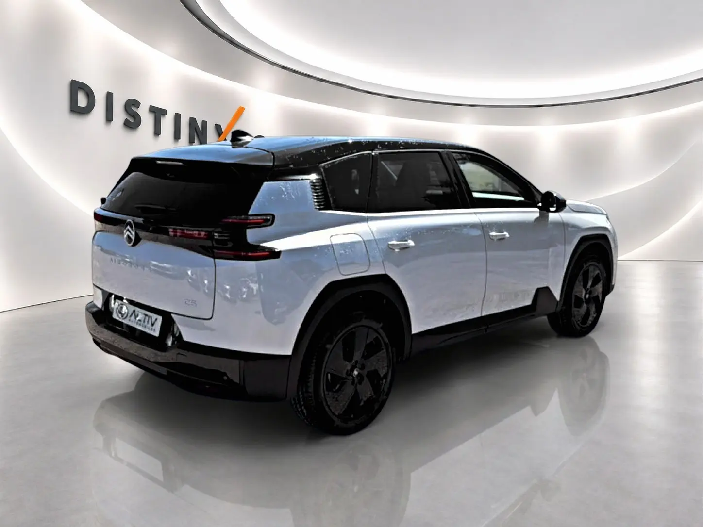 Vue 3/4 arrière droite du Citroën C5 Aircross blanc à toit noir avec jantes alliage noires dans un showroom.