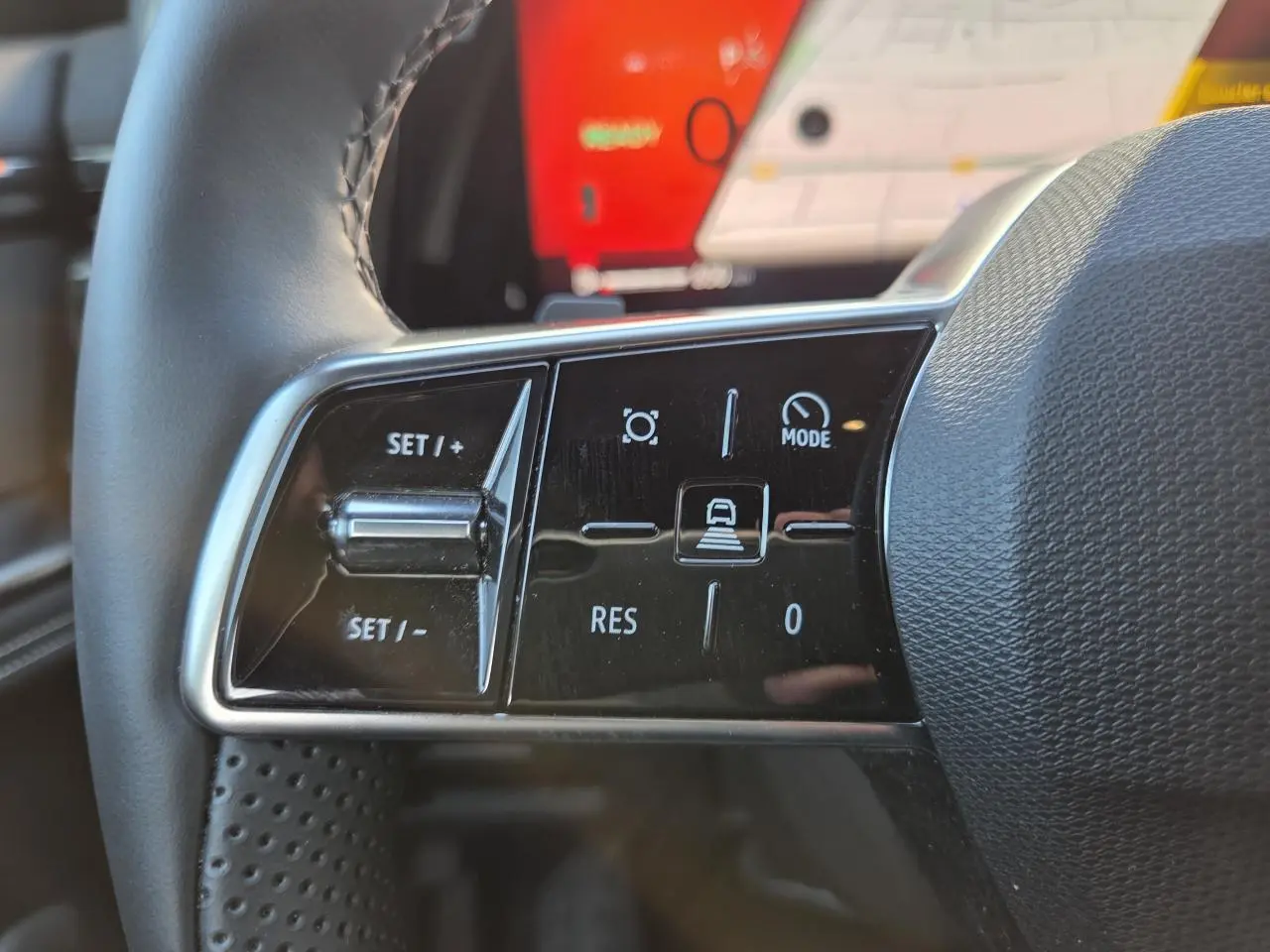 Gros plan sur les commandes du volant côté gauche du Renault Austral blanc nacré, avec écran tactile en arrière-plan.