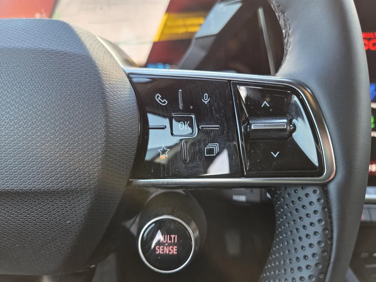 Gros plan sur les commandes gauche du volant noir perforé du Renault Austral 2025 avec bouton MULTI-SENSE illuminé.
