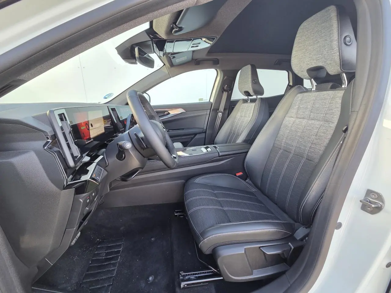 Vue intérieure côté conducteur du Renault Austral blanc nacré, sièges tissu et cuir, toit panoramique noir étoilé.