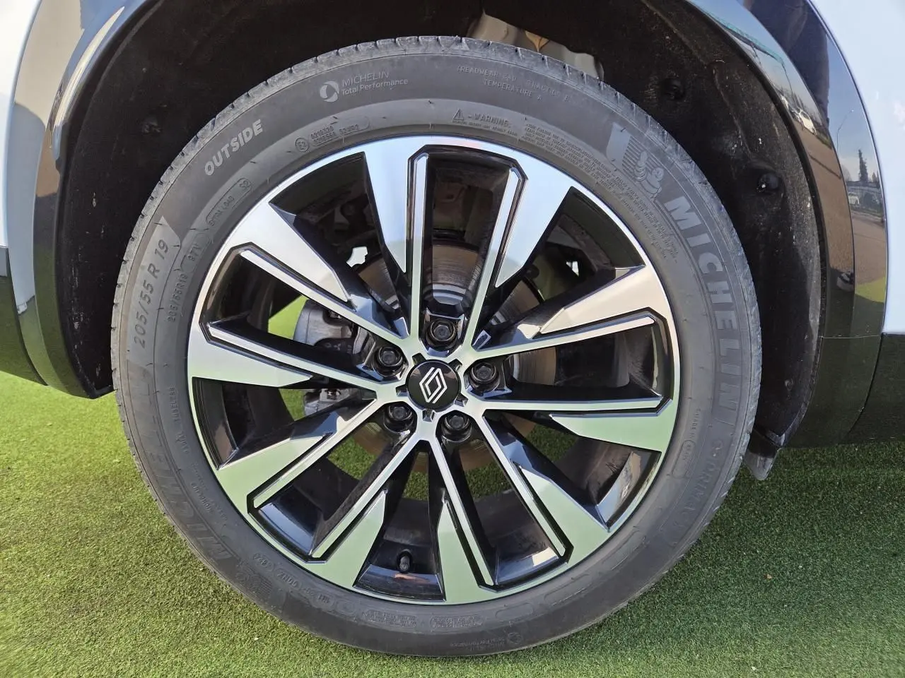 Gros plan sur la jante alliage 19 pouces noire et diamantée du Renault Austral blanc nacré avec toit noir.