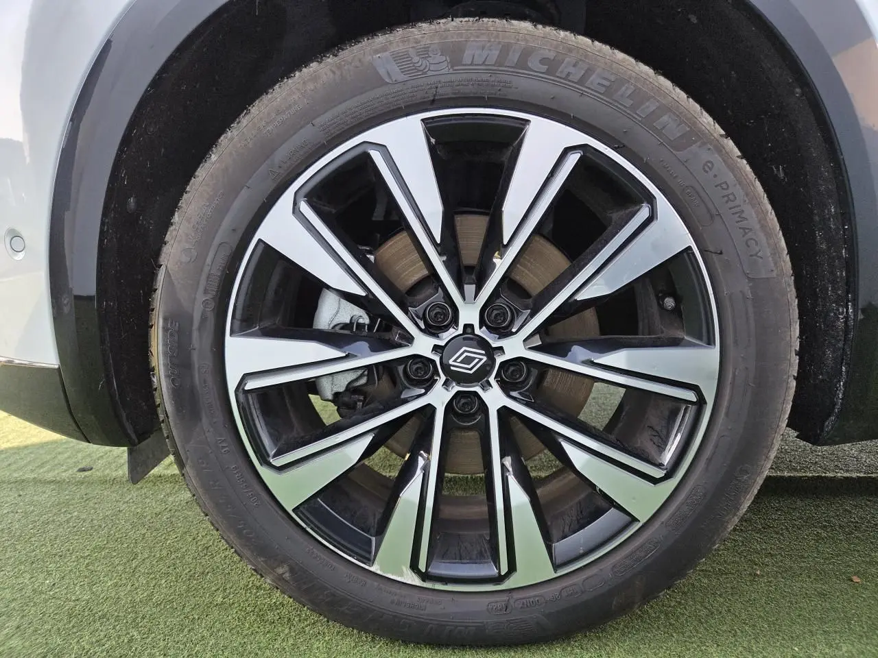 Gros plan sur la jante alliage noire et argentée du côté gauche d'un Renault Austral blanc nacré.