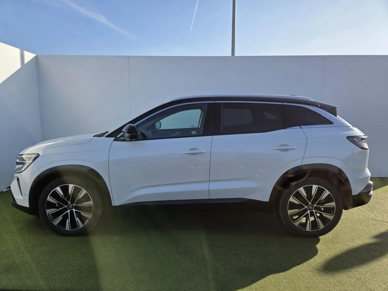 Profil droit du Renault Austral blanc nacré avec toit noir étoilé et jantes alliage noires diamantées.