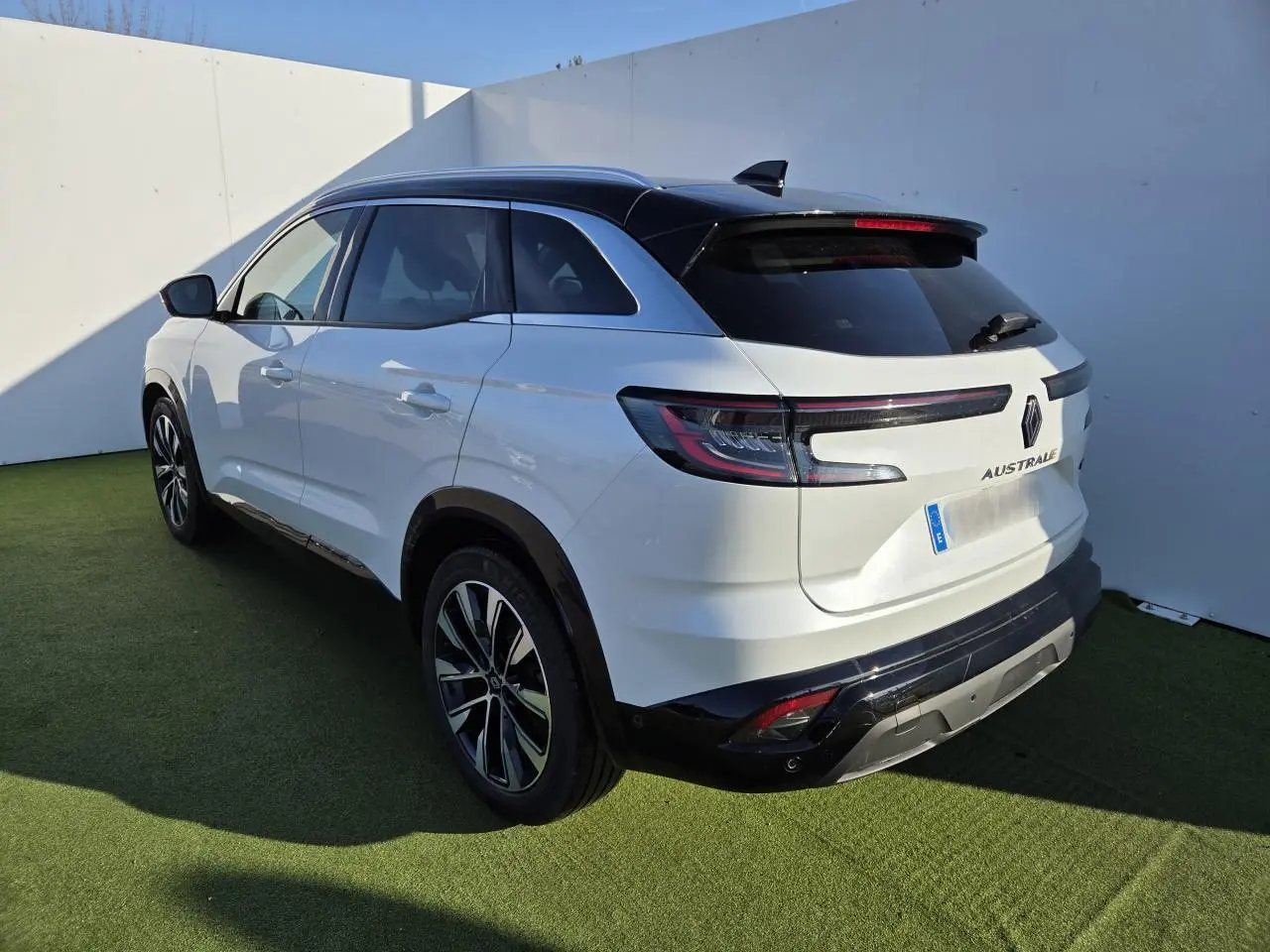 Vue 3/4 arrière droite du Renault Austral blanc nacré avec toit noir et jantes alliage noires diamantées.