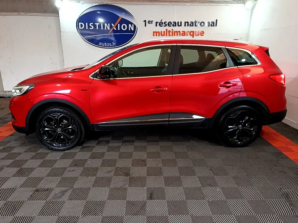 Vue de profil côté gauche d'un Renault Kadjar rouge SL Black Edition avec jantes noires brillantes en intérieur showroom.