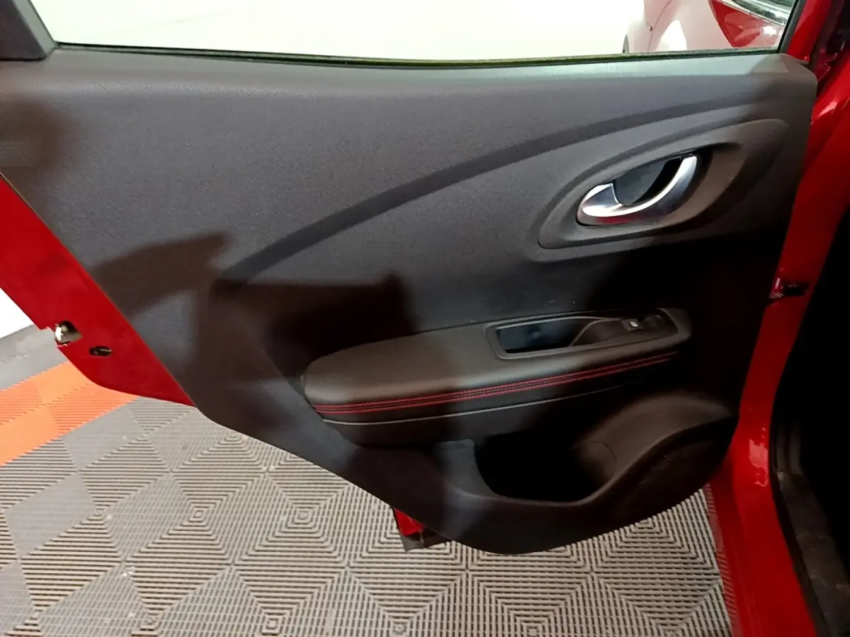 Vue rapprochée de la porte arrière gauche rouge du Renault Kadjar avec accoudoir noir et surpiqûres rouges.