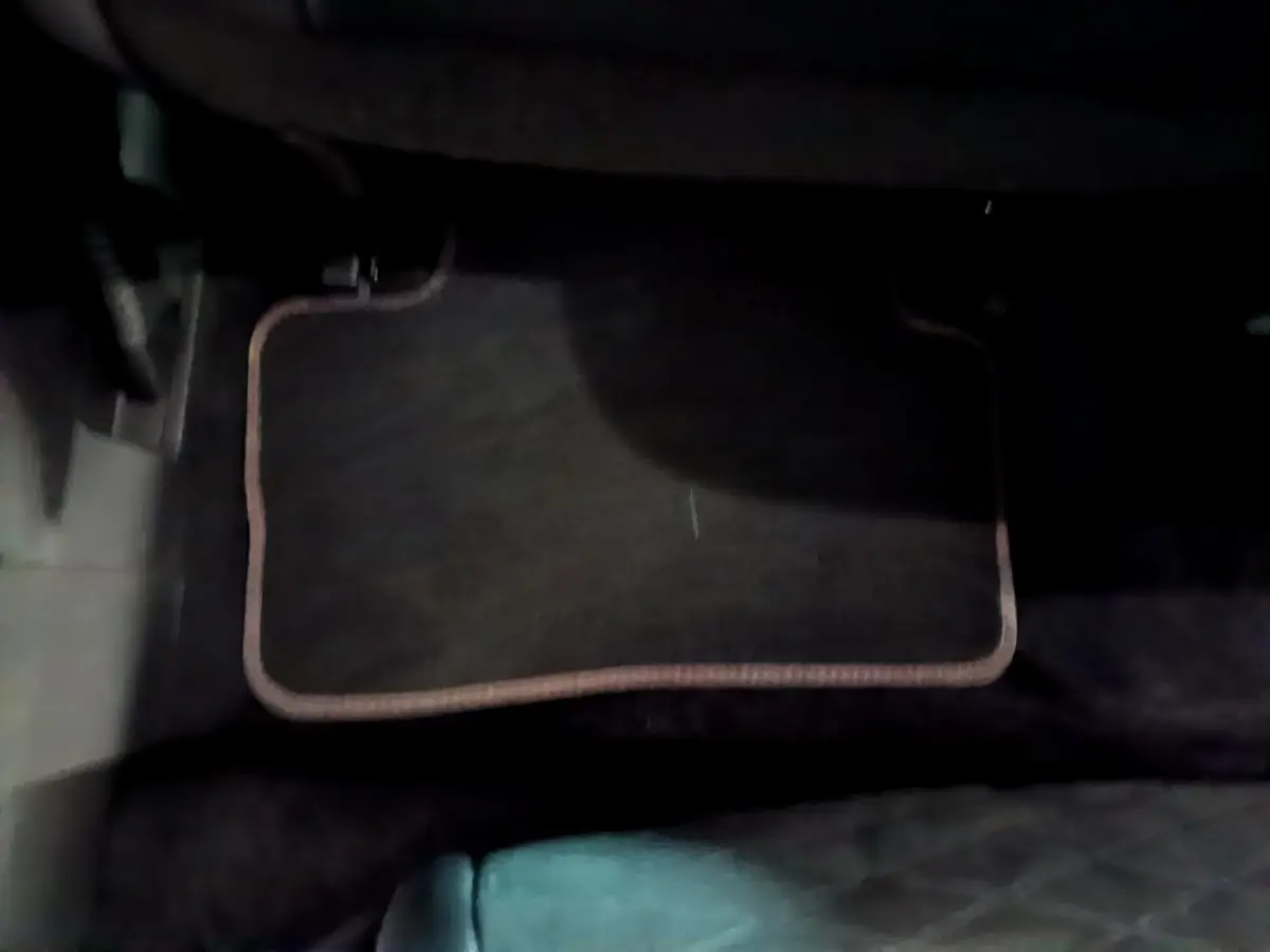 Tapis de sol noir avec bordure beige dans l'habitacle d'un Renault Kadjar rouge, vue côté conducteur.