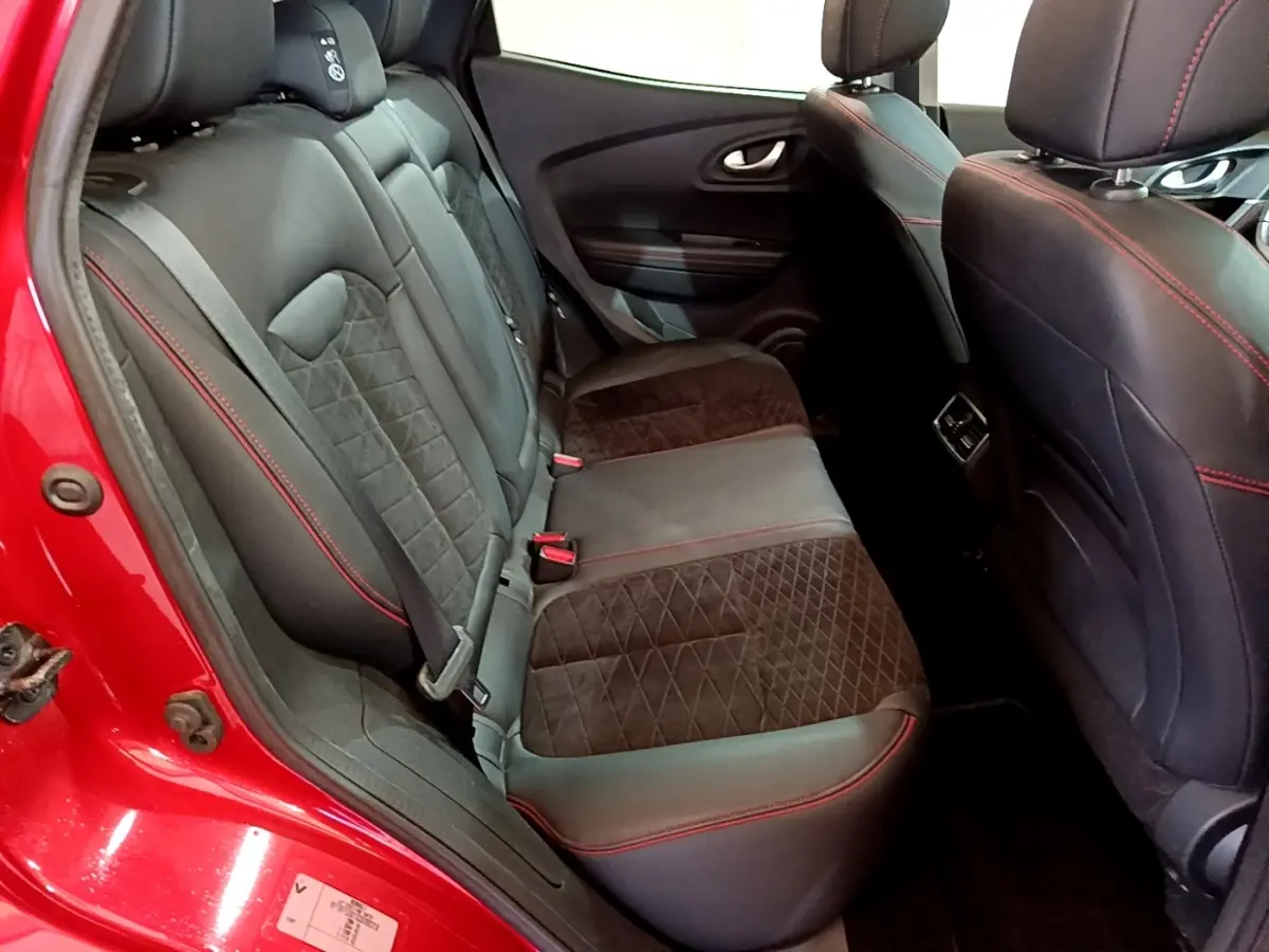 Vue intérieure arrière gauche du Renault Kadjar rouge, sièges noirs avec surpiqûres rouges et tissu matelassé.