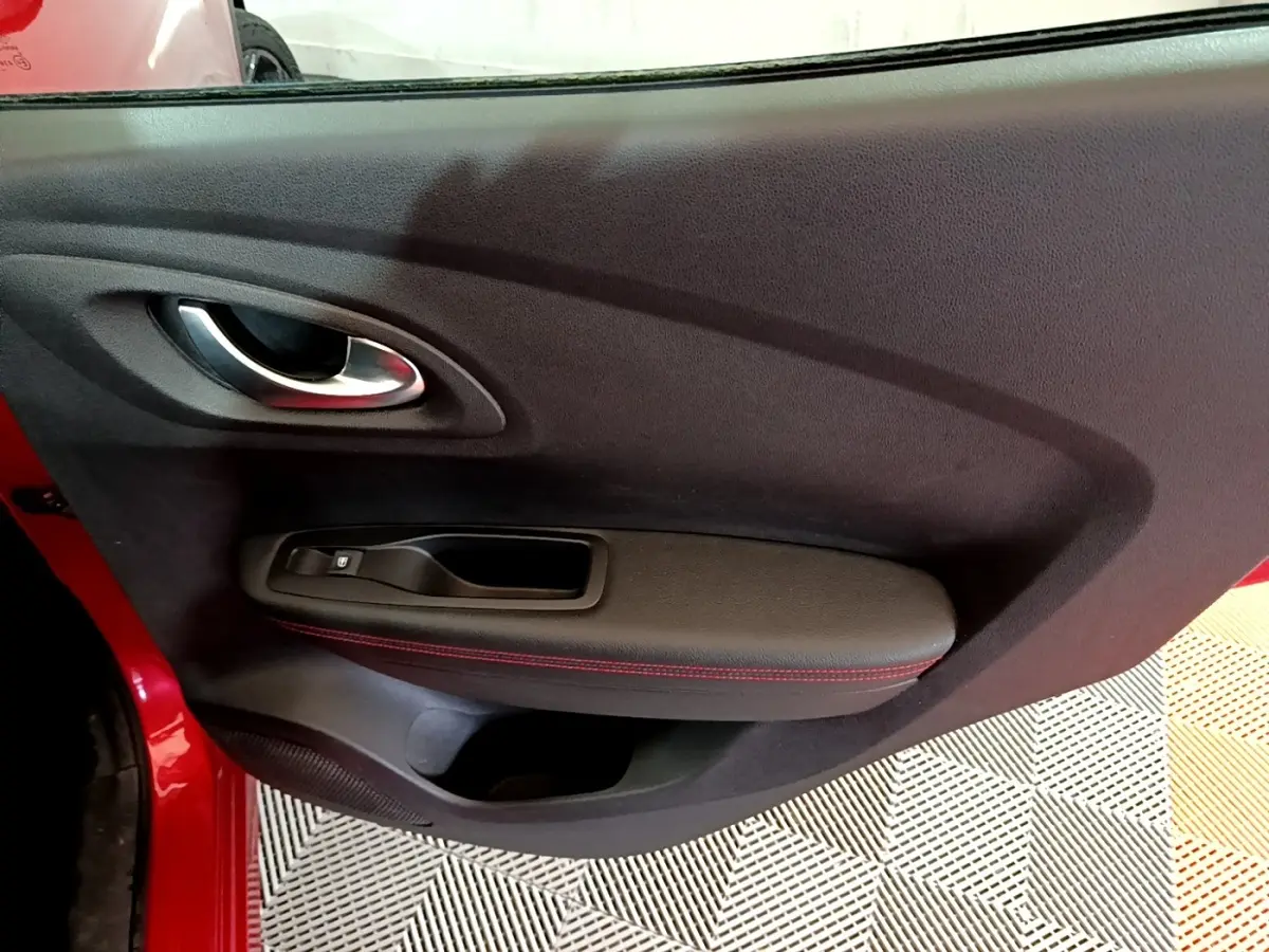 Vue rapprochée de la porte intérieure côté gauche rouge du Renault Kadjar avec poignée argentée et surpiqûres rouges.