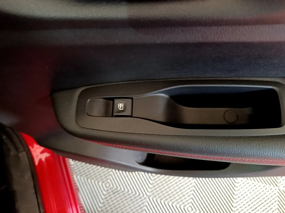 Gros plan sur la commande de lève-vitre côté conducteur du Renault Kadjar rouge, avec surpiqûres rouges visibles.