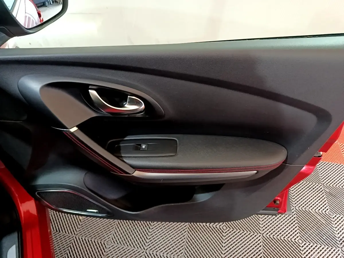 Vue rapprochée de la porte avant gauche rouge du Renault Kadjar 2019 avec poignée chrome et surpiqûres rouges.