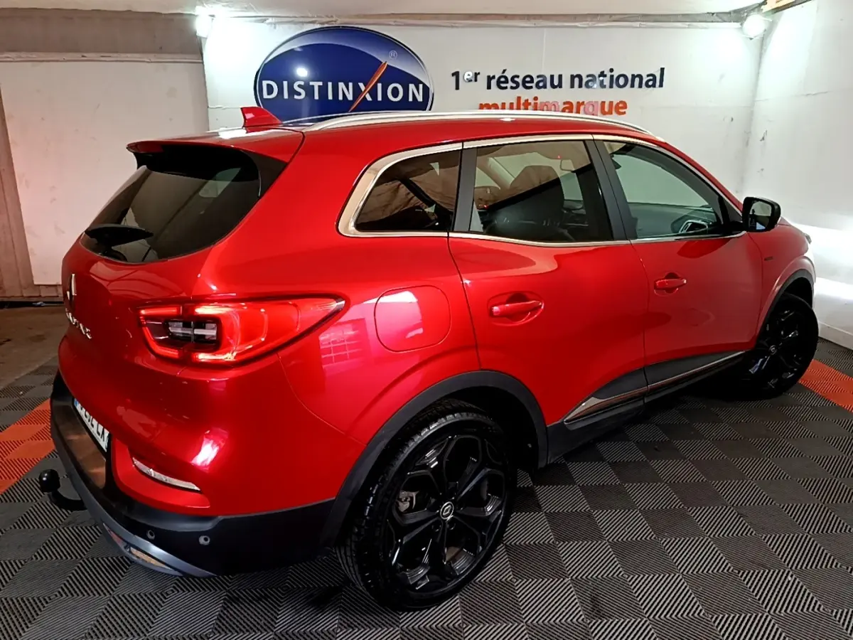 Vue 3/4 arrière droite du Renault Kadjar SL Black Edition rouge avec jantes noires et vitres teintées en intérieur showroom.