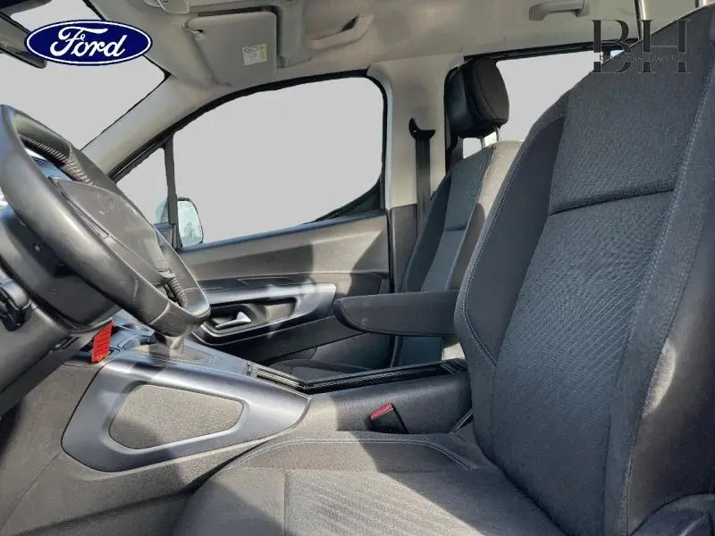 Vue intérieure côté conducteur du Peugeot Rifter 2020, sièges tissu gris avec accoudoir central noir.