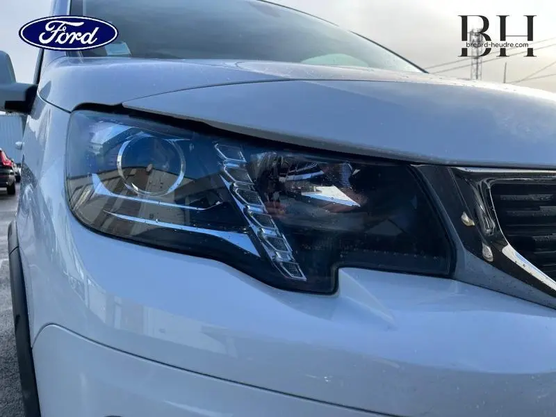 Gros plan sur le phare avant gauche blanc banquise du Peugeot Rifter 2020 avec calandre chromée et détails LED visibles.