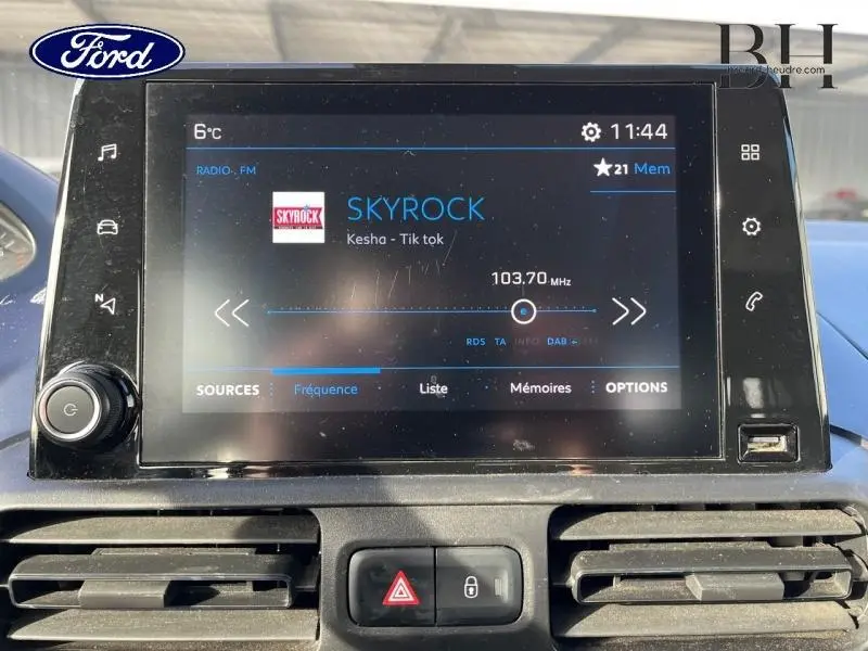 Je ne vois pas de véhicule Peugeot Rifter blanc dans cette image, mais un écran tactile d'infodivertissement avec l'interface radio affichant la station Skyrock.